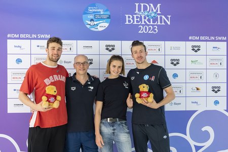 Malte Braunschweig, Elena Semechin, Matthias Ulm und Ole Braunschweig stehen nebeneinander vor einer Werbewand der IDM Berlin 2023.