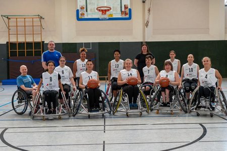 Teamfoto der Rollstuhlbasketballerinnen in weißen Trikots.