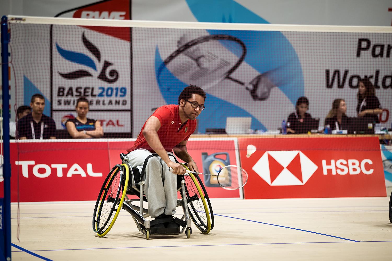 Badmintonspieler im Rollstuhl am Netz schaut zum Ball.