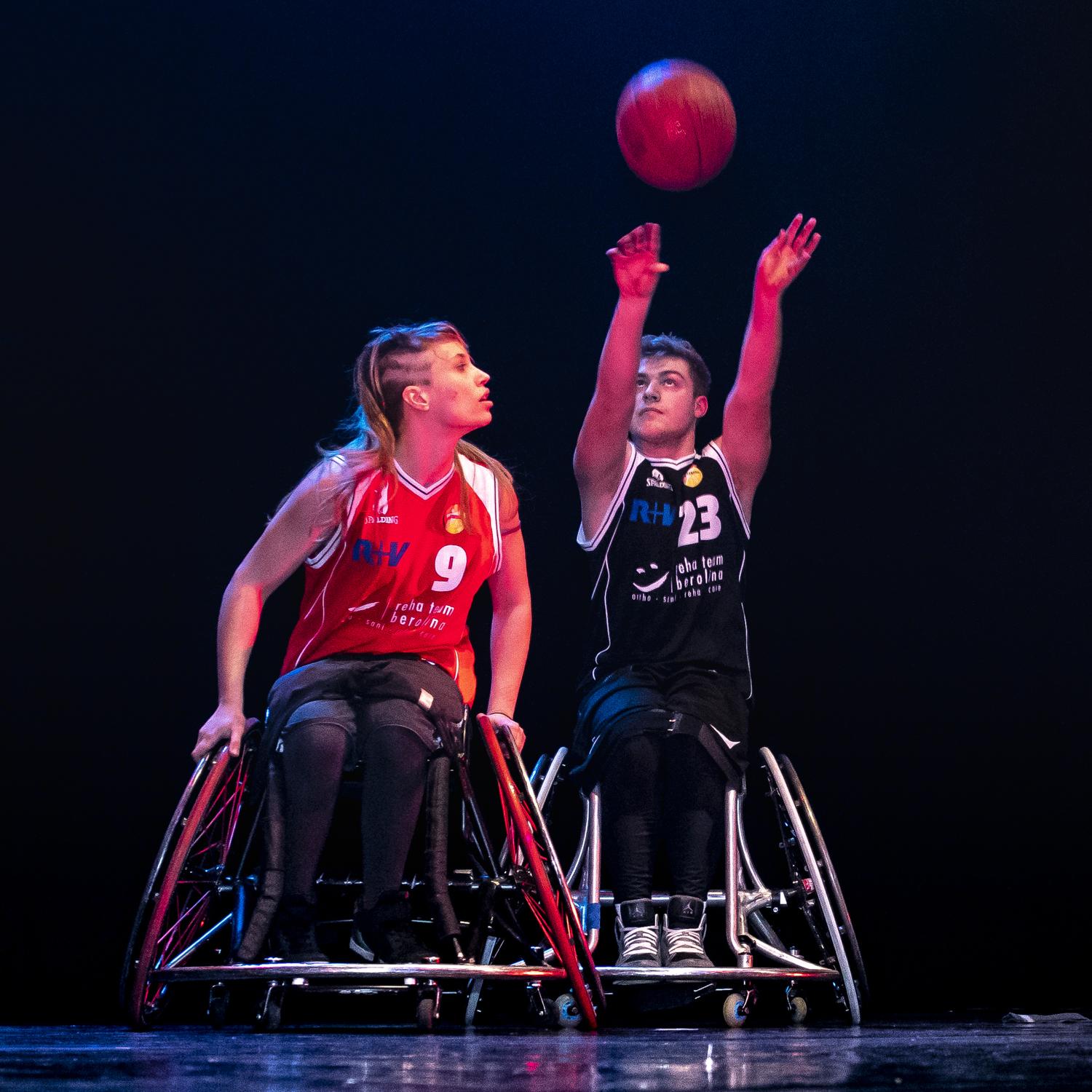 Zwei Rollstuhlbasketballer im Zweikampf. Der Ball ist über ihnen in der Luft.